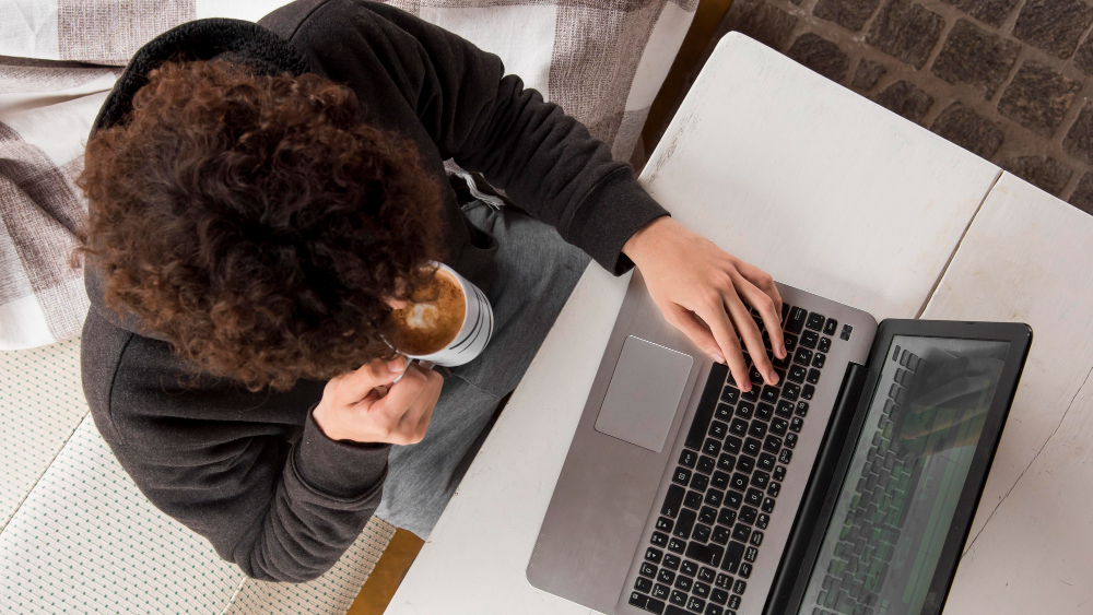 Person drinking coffee and working on laptop computer