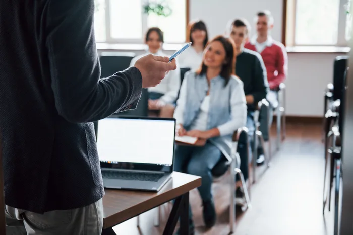 Teacher with laptop teaching a class of adults